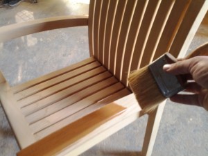 Brushing teak sealer onto a teak patio chair